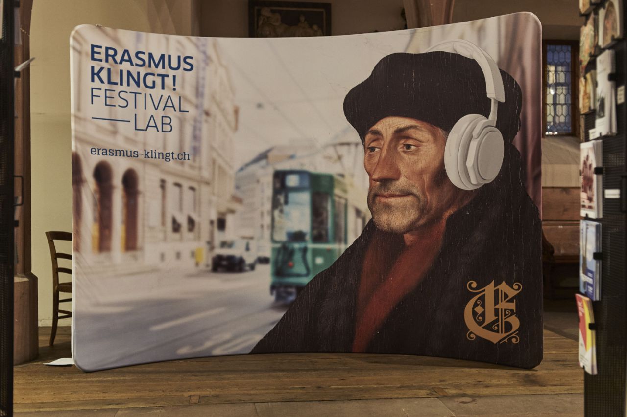 Festival Erasmus Klingt: grosses Plakat mit dem Portrait von Erasmus mit Kopfhörern und Tram im Hintergrund