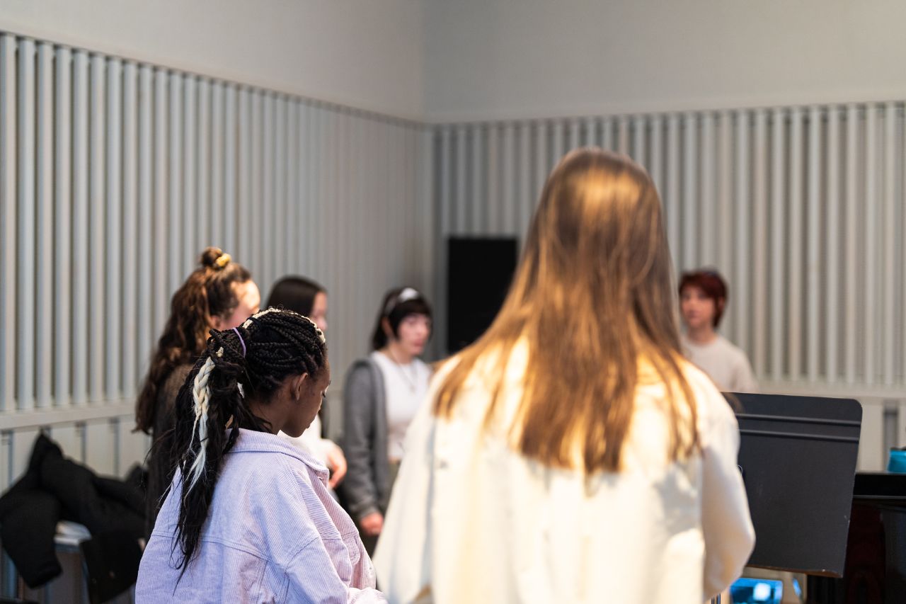 Fünf jugendliche Schüler:innen singen zusammen im Kreis.