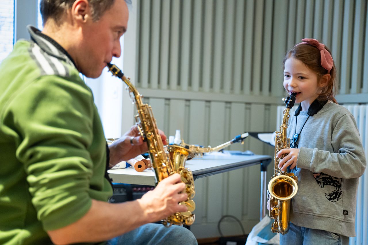 Ein Mann und ein Mädchen spielen beide Saxophon. 